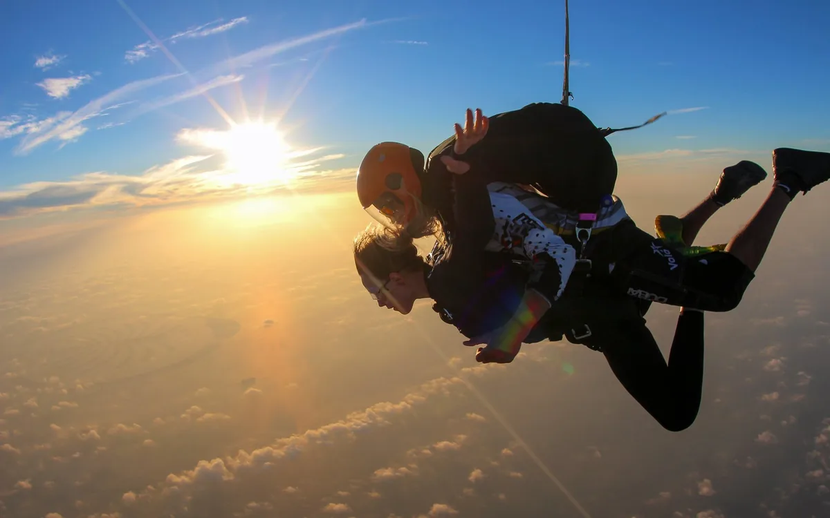 A tandem skydiver in freefall over Dubai at sunset