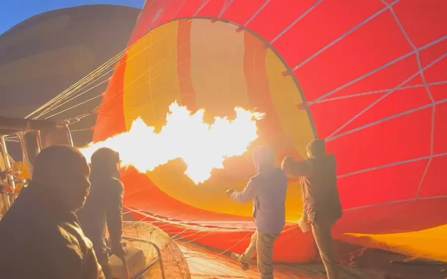 A hot air balloon inflating in the desert at dawn