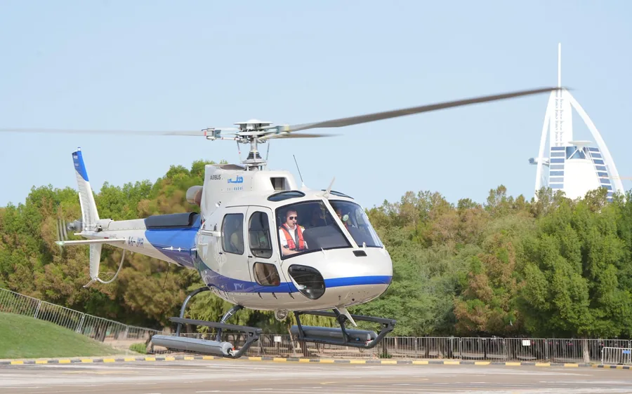 A helicopter on the pad with the Burj Al Arab behind it